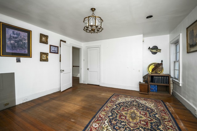 interior space featuring dark wood-type flooring, a notable chandelier, and baseboards