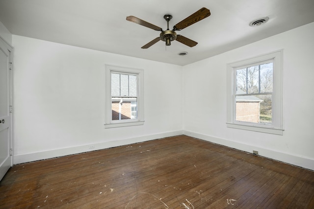 spare room featuring visible vents, dark wood finished floors, baseboards, and ceiling fan