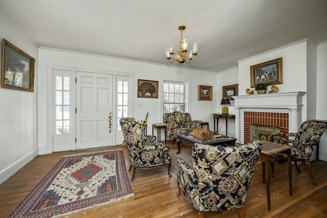 foyer featuring a brick fireplace, ornamental molding, wood finished floors, and an inviting chandelier