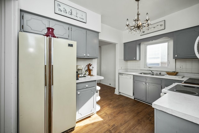 kitchen featuring hanging light fixtures, white appliances, light countertops, and a sink