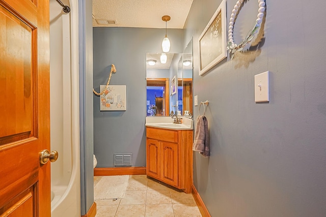 bathroom with tile patterned floors, toilet, a textured ceiling, and vanity