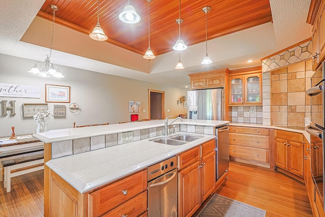 kitchen with a raised ceiling, sink, and a center island with sink