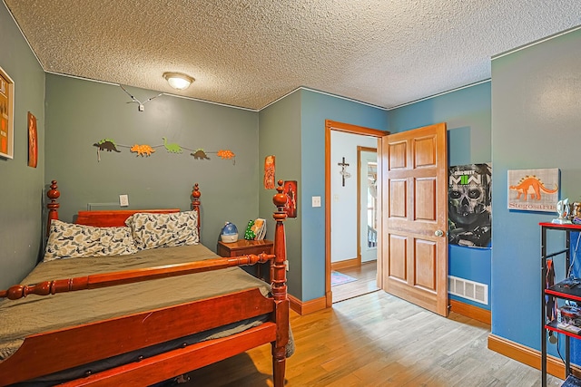 bedroom with light hardwood / wood-style floors and a textured ceiling