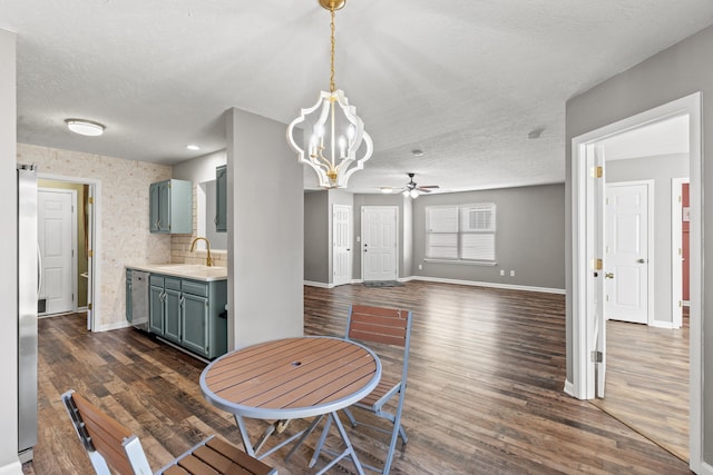 dining area with sink, ceiling fan with notable chandelier, dark wood-type flooring, and a textured ceiling