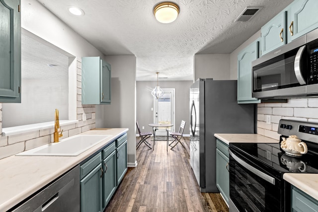 kitchen with dark wood-type flooring, sink, decorative light fixtures, appliances with stainless steel finishes, and backsplash