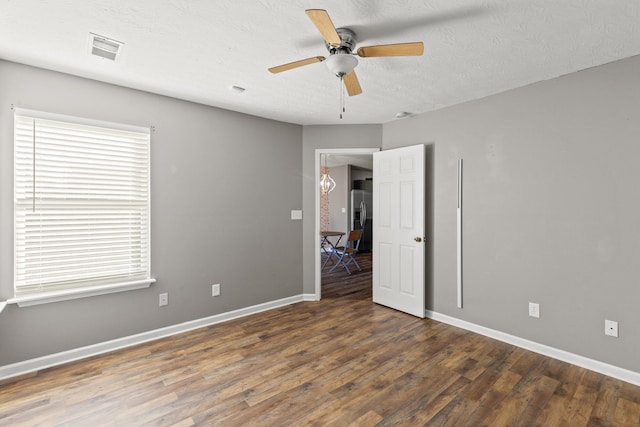 unfurnished room featuring dark wood-type flooring, ceiling fan, and a textured ceiling