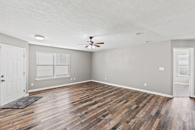 interior space with dark wood-type flooring, ceiling fan, a textured ceiling, and a wealth of natural light