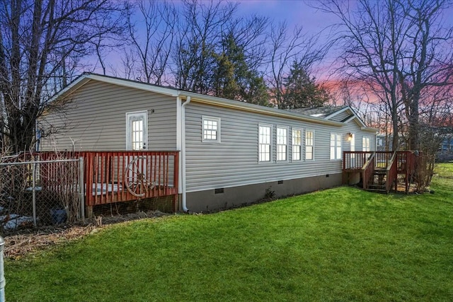 back house at dusk with a wooden deck and a yard