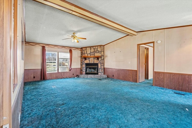 unfurnished living room with a fireplace, lofted ceiling with beams, a textured ceiling, dark carpet, and wood walls