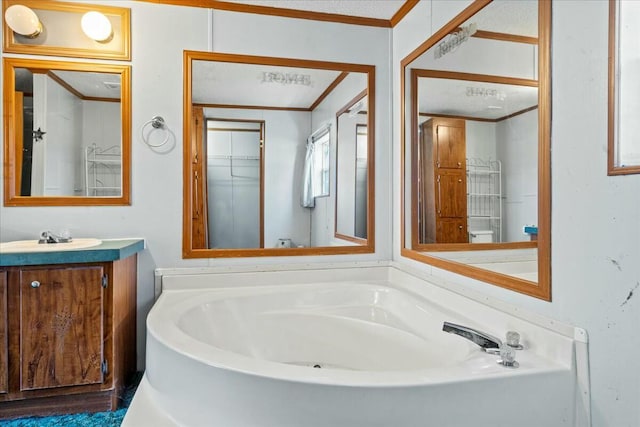 bathroom with ornamental molding, vanity, and a bathtub