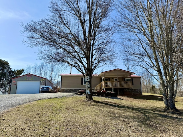 manufactured / mobile home featuring an outbuilding, metal roof, a garage, a wooden deck, and a front lawn