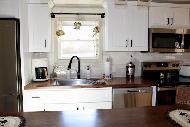 kitchen featuring sink, wooden counters, white cabinets, backsplash, and stainless steel appliances