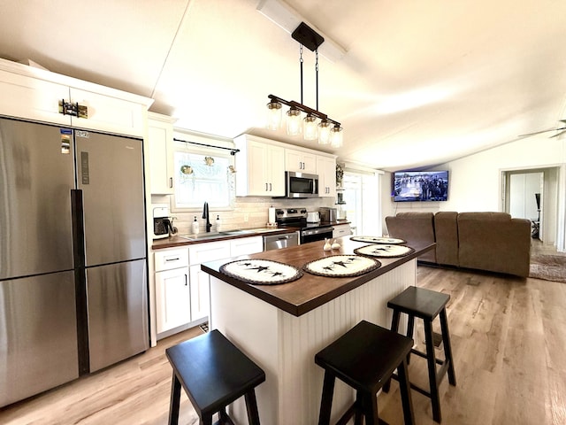 kitchen with white cabinetry, vaulted ceiling, a breakfast bar area, and stainless steel appliances