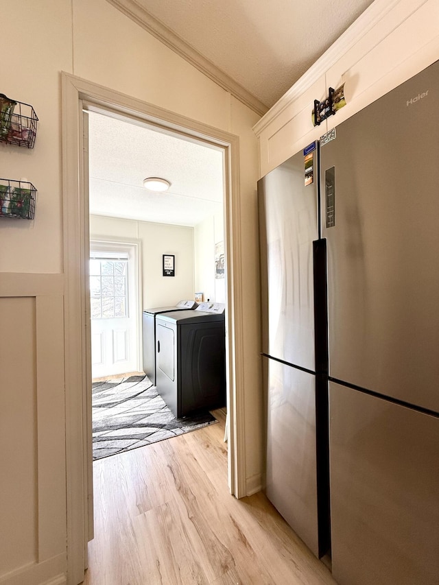 interior space featuring light wood-style floors, crown molding, and washer and dryer