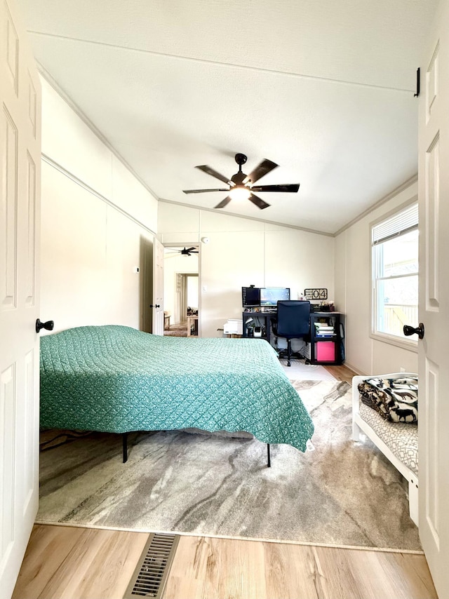 bedroom with crown molding, visible vents, ceiling fan, and wood finished floors