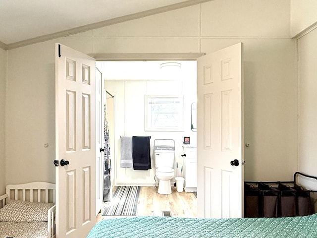 bedroom with vaulted ceiling and wood finished floors