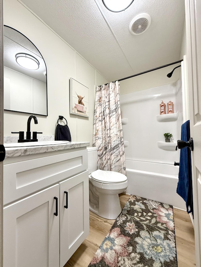 bathroom featuring a textured ceiling, toilet, wood finished floors, and visible vents