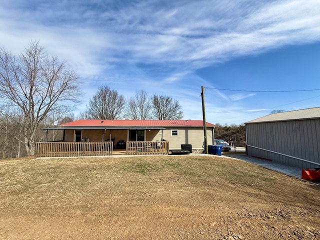 rear view of property featuring covered porch, a yard, metal roof, and an outdoor structure