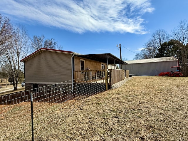 view of side of property featuring a pole building, an outdoor structure, and fence