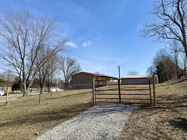 view of gate with a yard, an outbuilding, a pole building, and fence