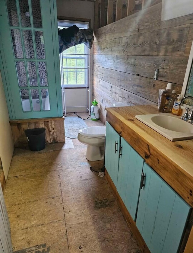 bathroom with vanity, toilet, and wood walls