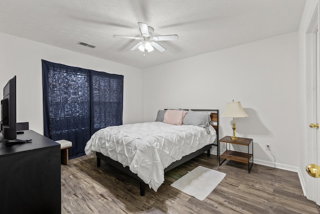 bedroom with ceiling fan, hardwood / wood-style flooring, and a textured ceiling