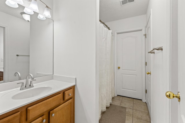 bathroom with tile patterned floors, a textured ceiling, and vanity