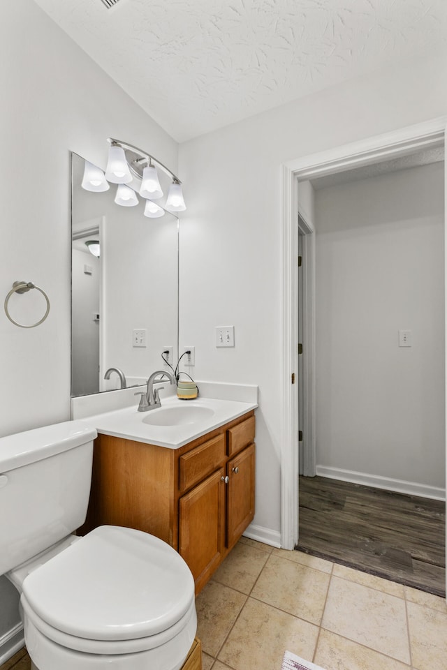 bathroom featuring tile patterned floors, vanity, toilet, and a textured ceiling