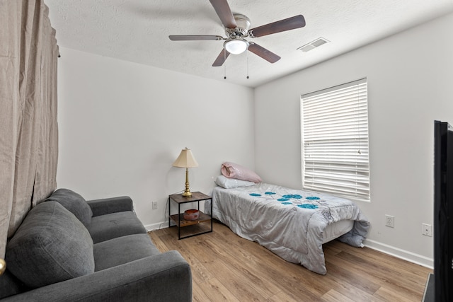 bedroom featuring ceiling fan, a textured ceiling, and light wood-type flooring