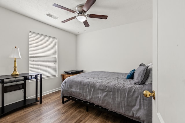 bedroom with ceiling fan, wood-type flooring, and a textured ceiling