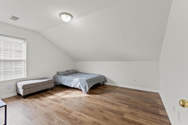 bedroom with hardwood / wood-style flooring and lofted ceiling