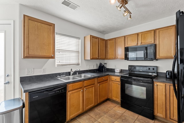 kitchen with sink, light tile patterned floors, black appliances, and a textured ceiling