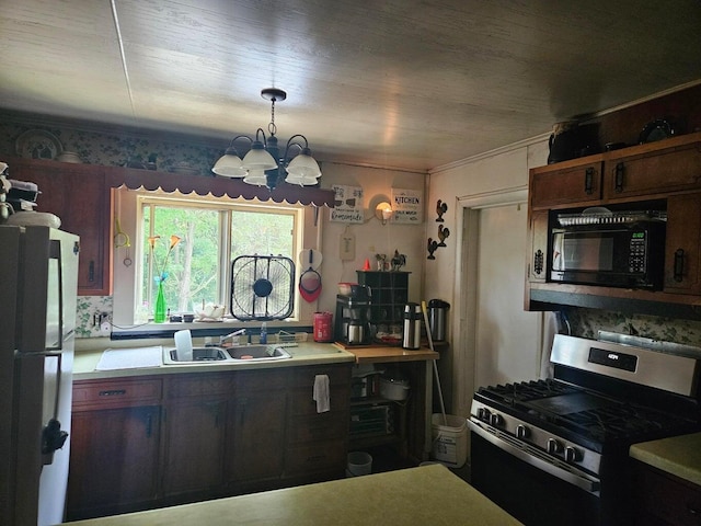 kitchen with stainless steel gas range, sink, decorative light fixtures, fridge, and a notable chandelier