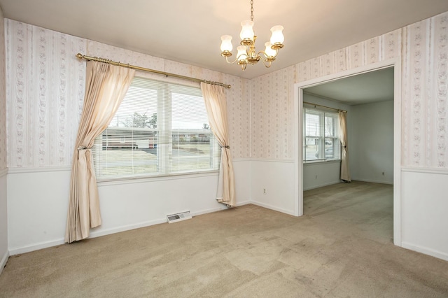 spare room with an inviting chandelier and light colored carpet