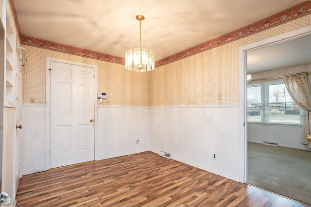 unfurnished room featuring hardwood / wood-style floors and an inviting chandelier