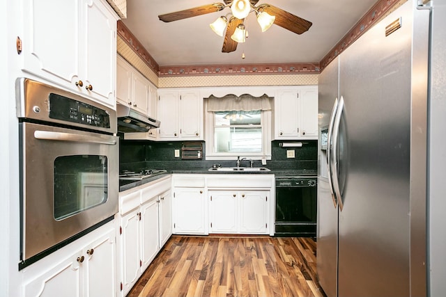 kitchen featuring sink, appliances with stainless steel finishes, hardwood / wood-style flooring, decorative backsplash, and white cabinets