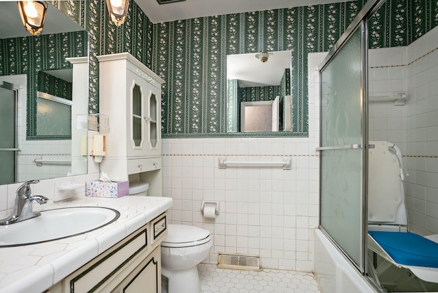 full bathroom featuring tile walls, vanity, shower / bath combination with glass door, and toilet