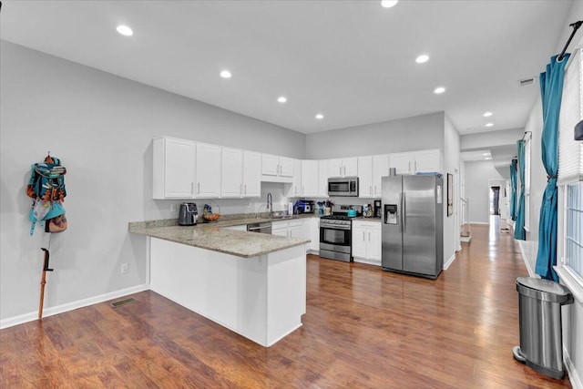 kitchen with white cabinetry, appliances with stainless steel finishes, dark hardwood / wood-style flooring, and kitchen peninsula