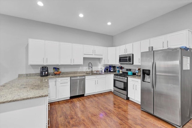 kitchen with stainless steel appliances, sink, hardwood / wood-style floors, and white cabinets