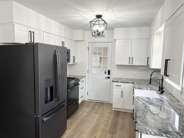 kitchen featuring white cabinetry, stone countertops, sink, and black appliances