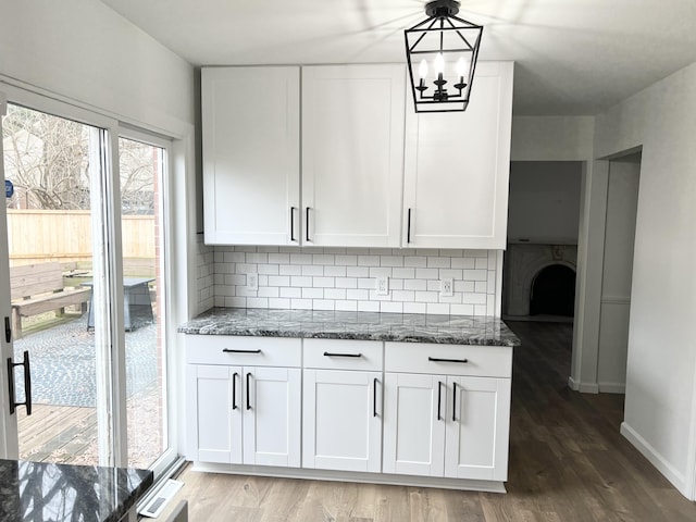 kitchen featuring white cabinetry, dark stone counters, decorative light fixtures, and tasteful backsplash