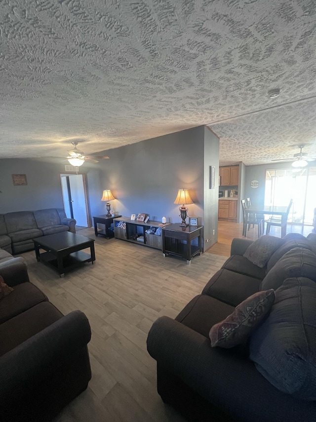 living room with hardwood / wood-style flooring, ceiling fan, and a textured ceiling