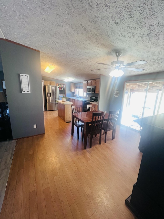 dining room featuring ceiling fan, sink, and light hardwood / wood-style flooring