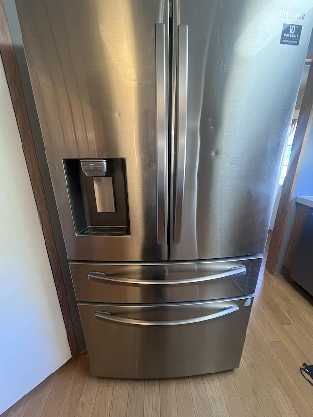 interior details featuring stainless steel refrigerator with ice dispenser and light hardwood / wood-style floors