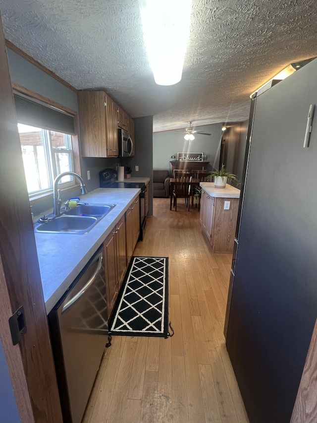 kitchen featuring sink, light hardwood / wood-style flooring, a textured ceiling, ceiling fan, and stainless steel appliances