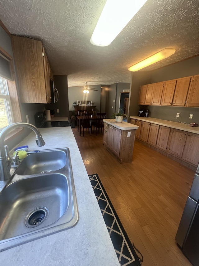 kitchen featuring a center island, sink, dark wood-type flooring, and a textured ceiling