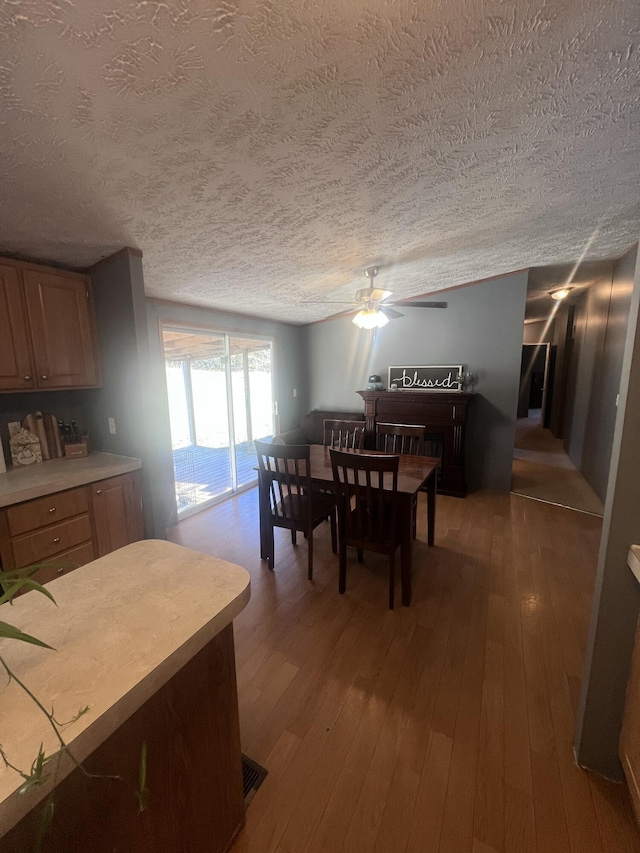 dining area featuring hardwood / wood-style flooring, a textured ceiling, and ceiling fan