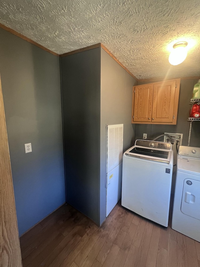 washroom with cabinets, washing machine and dryer, dark hardwood / wood-style floors, and a textured ceiling