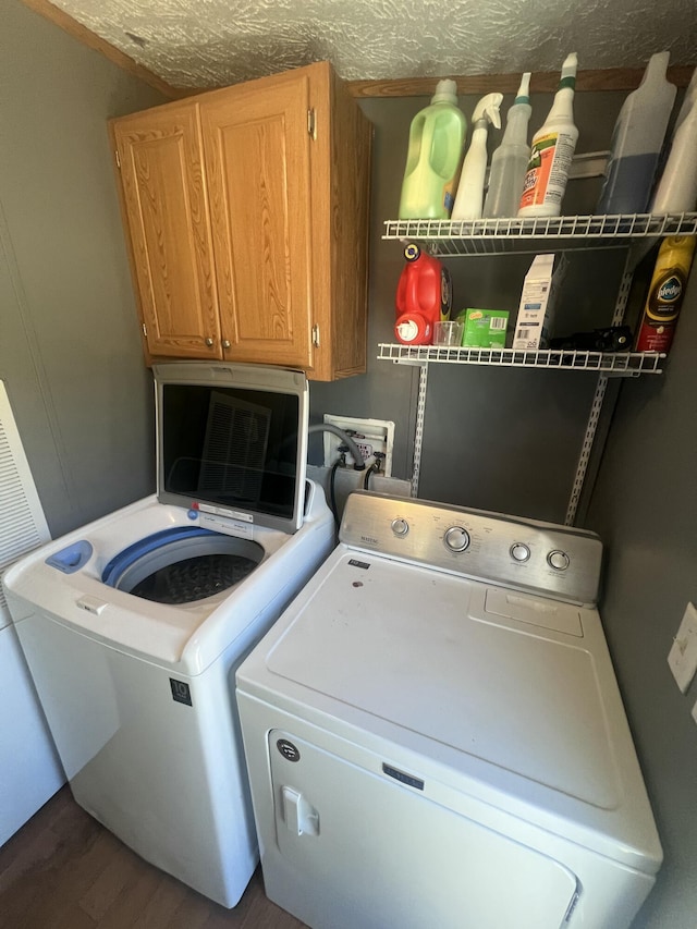 clothes washing area with cabinets, dark hardwood / wood-style flooring, a textured ceiling, and washer and clothes dryer