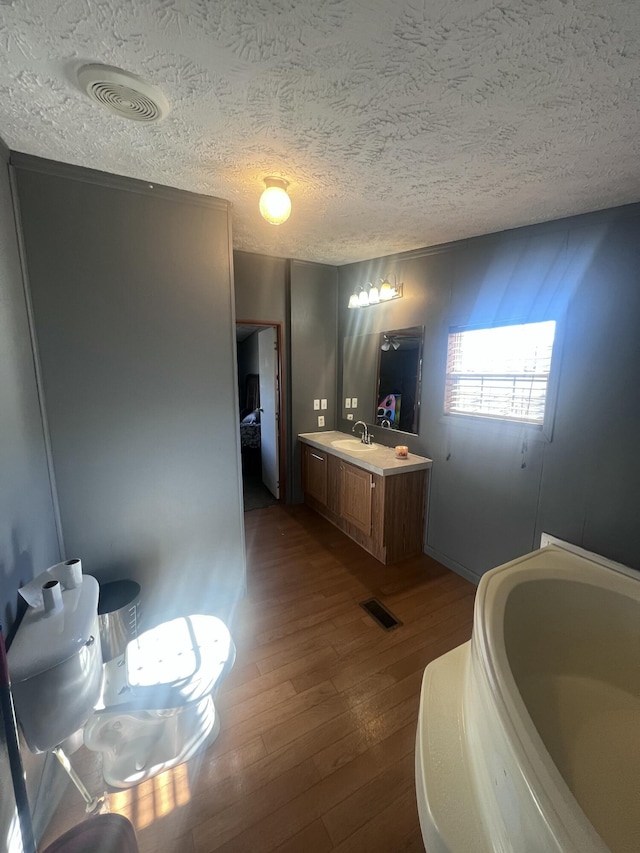 bathroom with vanity, hardwood / wood-style flooring, a tub, and a textured ceiling